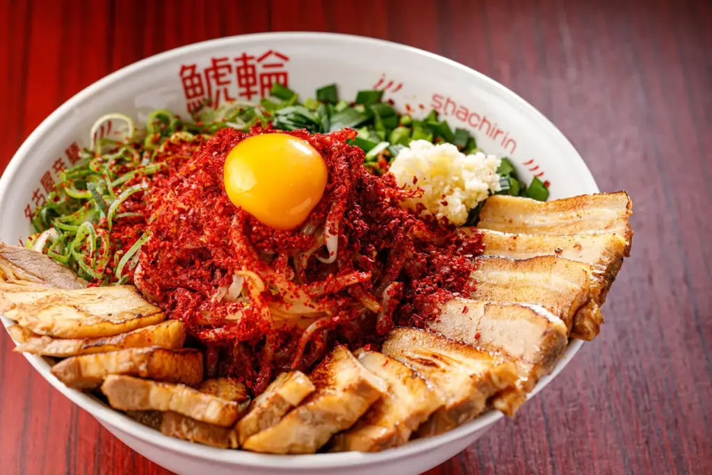 名古屋辛麺 鯱輪の旨辛赤まぜそばに卵黄とニラがのった料理写真
